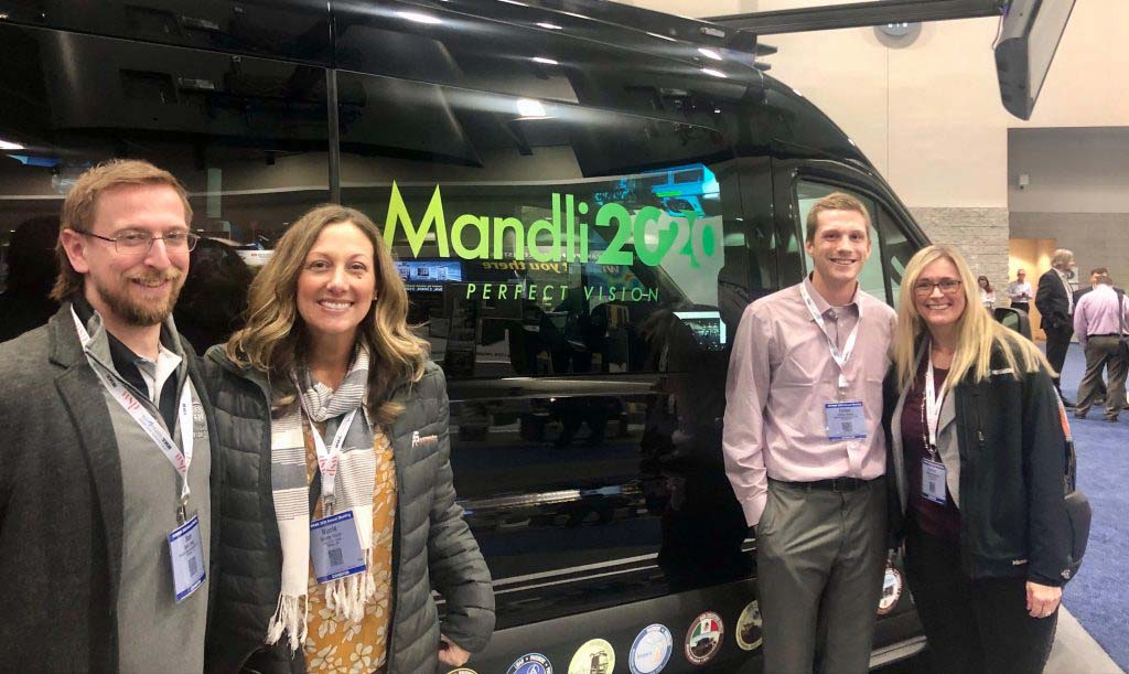 Four people standing in front of Mandli display